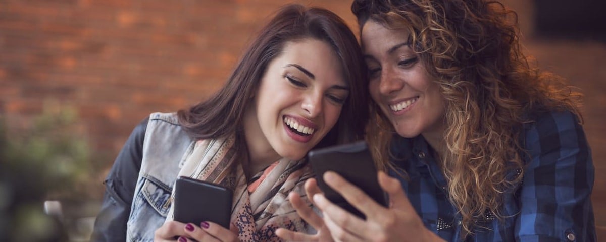 Deux femmes souriantes avec leur téléphone en main