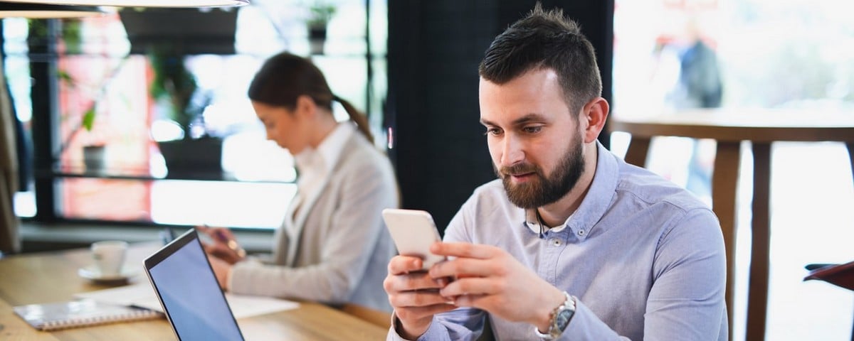 Un homme d'affaires utilise un téléphone portable et lit un message texte alors qu'il est assis au bureau. 