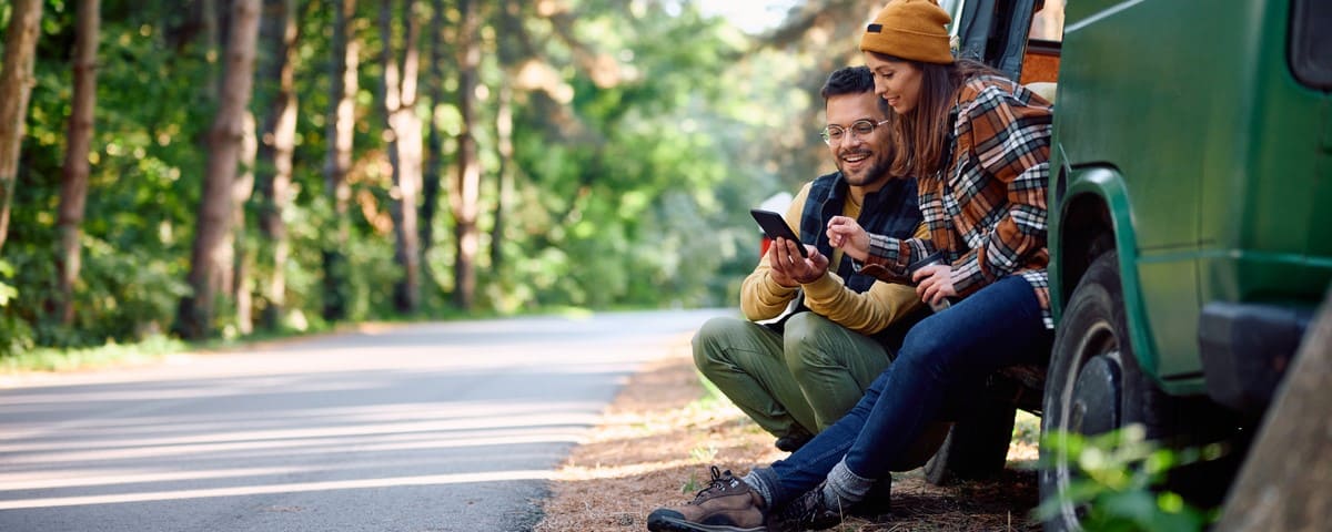 Jeune couple en road-trip sur leur téléphone